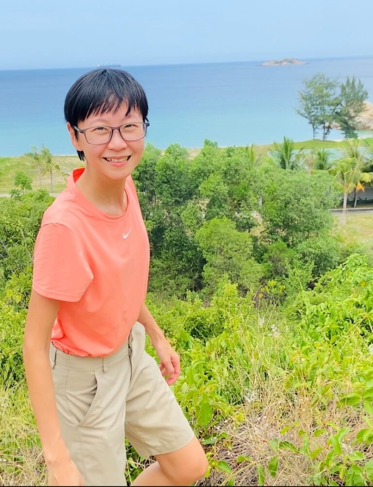 Trang Nguyen on a green hillside above the sea